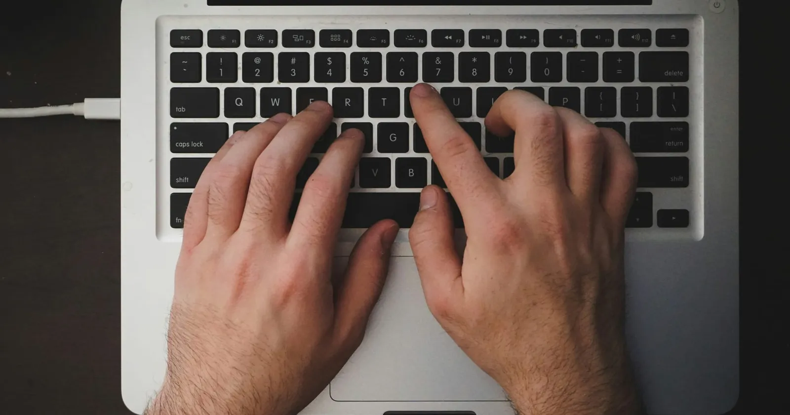 Picture of a man typing on the keyboard of his laptop